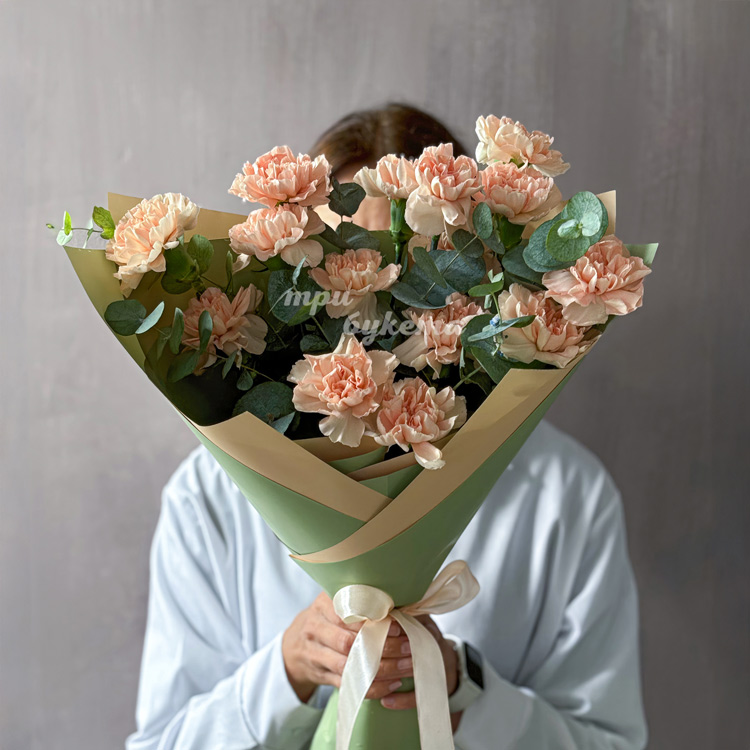 Букет из персиковых гвоздик и эвкалипта (в руках флориста)